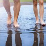 Man and woman walking through puddle.