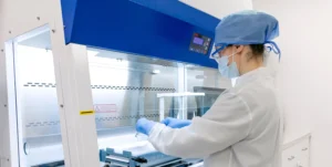 Lab technician loading medication into capsules in an exhaust hood.