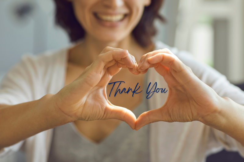 Woman with hands shaped into a heart with the words thank you between them.