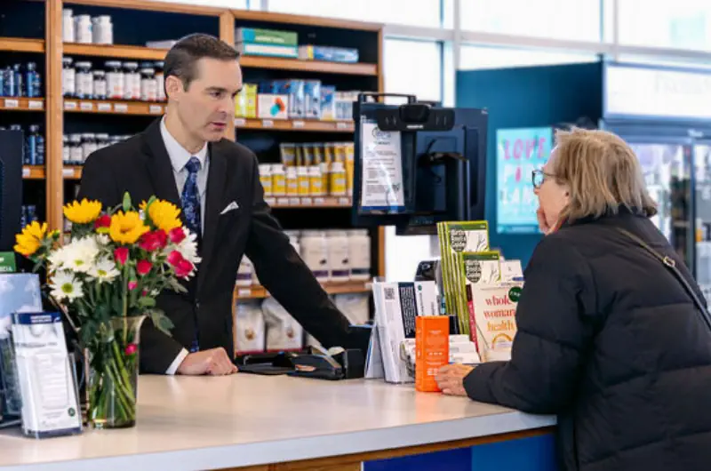 Wellness specialist in a suit and tie helping a customer at the store counter.