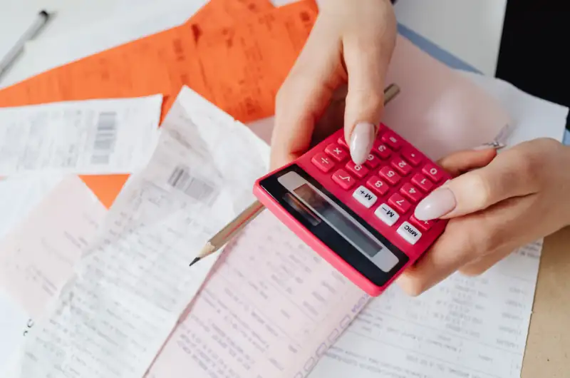 Woman using calculator with papers on the table,