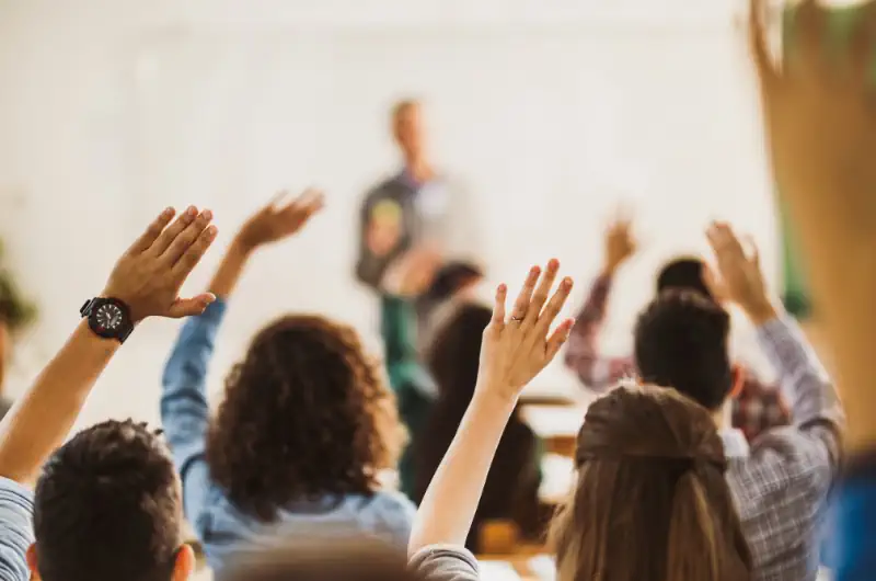 Room of people with their hands up for questions.