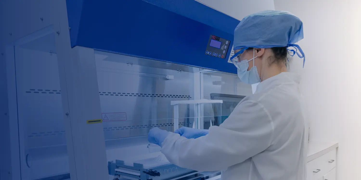 Lab technician loading medication into capsules in an exhaust hood. 